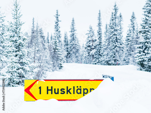 Winter Road Sign Indicating Huskläppen Amidst Snow-covered Trees in Sweden