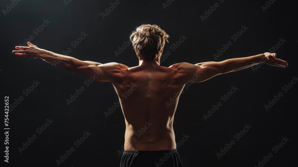 Obraz premium Rear view of healthy muscular young man with his arms stretched out isolated on black background