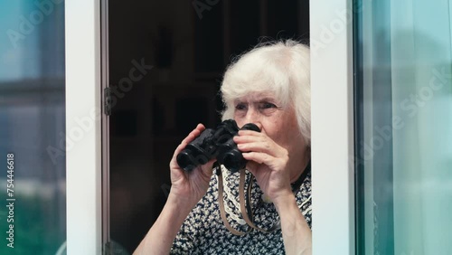 Humorous elderly woman watching people on the street using binoculars, spying
