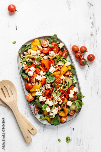 Roasted pepper and butter bean salad with harissa dressing on white background.