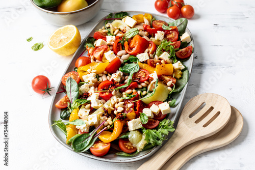 Roasted pepper and butter bean salad with harissa dressing on white background.