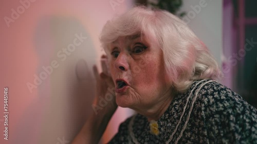 Humorous granny eavesdropping on her neighbors through the wall, funny woman photo