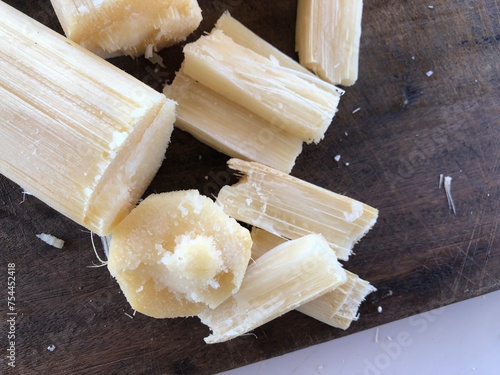 Sugar cane cut into pieces on wooden board with copy space photo