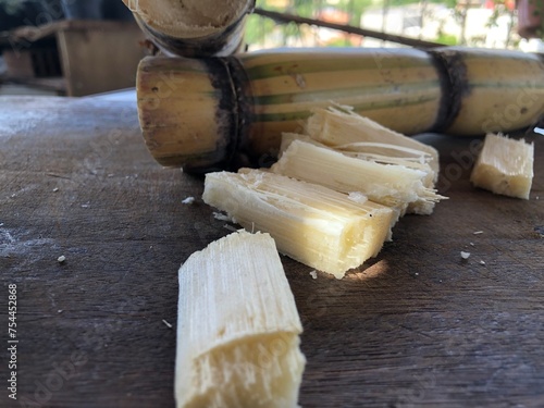 Sugar cane cut into pieces on wooden board with copy space photo