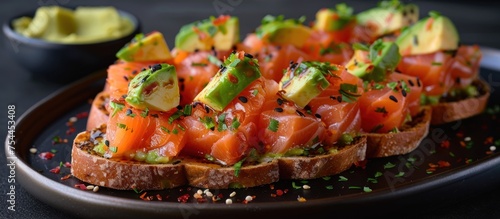 A black plate features slices of bread topped with fresh salmon and avocado. The colorful ingredients create an appetizing and nutritious meal.