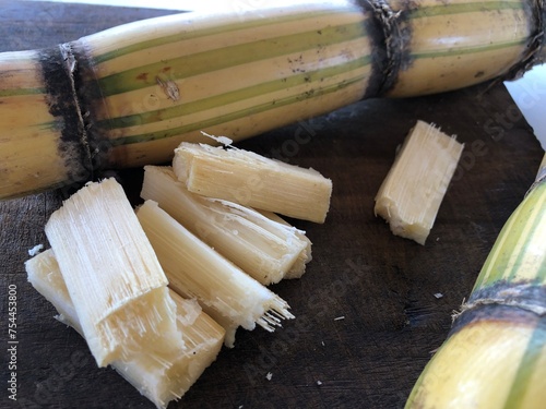 Sugar cane cut into pieces on wooden board with copy space photo