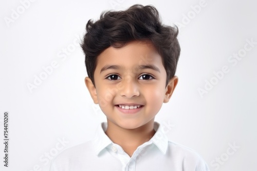 A young boy in a white shirt smiling at the camera. Ideal for family and children themes