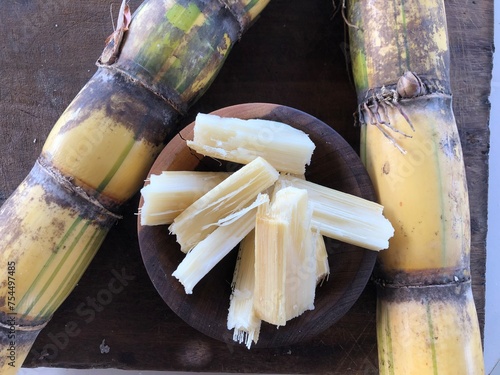 Sugar cane cut into pieces on wooden board with copy space photo