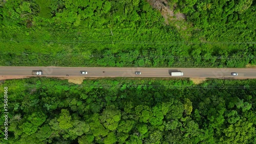 Aerial drone view of the vehicles on a paved highway cutting through the Amazon rainforest photo