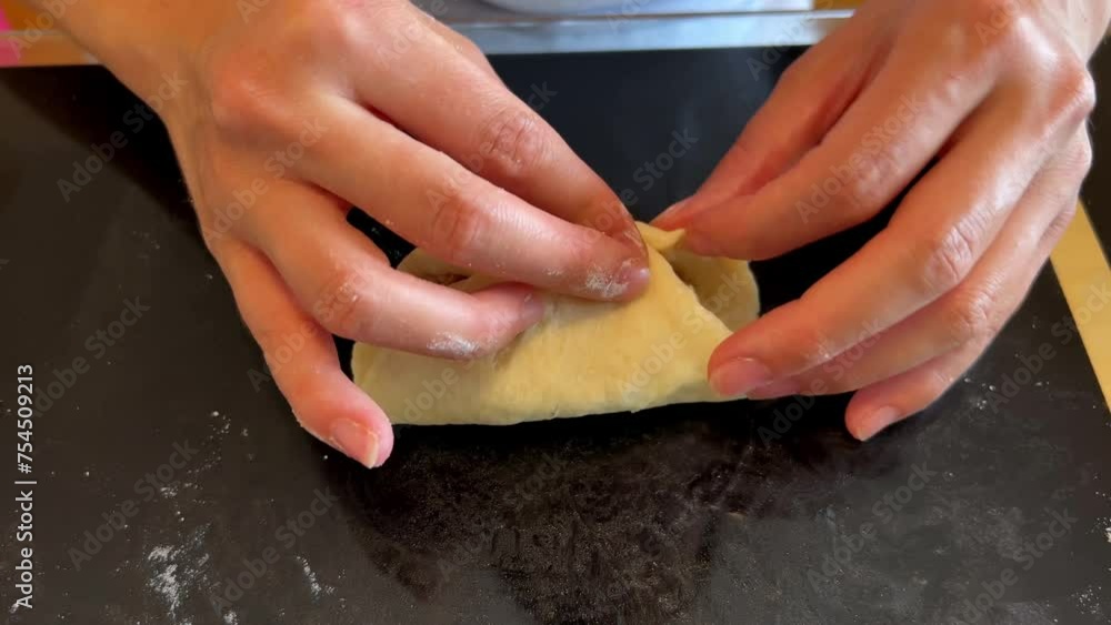 A person is holding a piece of dough with a piece of meat on it using their hand. They are preparing a recipe with these ingredients in the kitchen A person is holding a piece of dough with a piece of meat on it using their hand. They are preparing a recipe with these ingredients in the kitchen