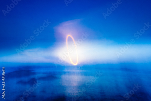 An abstract motion blurred light painting of the setting sun in a blue sky over the ocean along the California coast photo