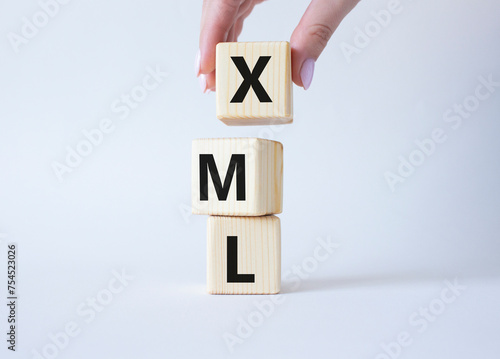 XML - Extensible Markup Language. Wooden cubes with word XML. Businessman hand. Beautiful white background. Business and Extensible Markup Language concept. Copy space. photo