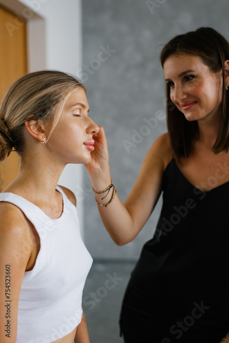 Makeup artist applies eye shadow to another woman