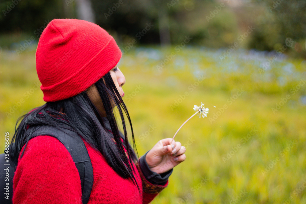Atractiva mujer Explorando la belleza invernal,Chica con mochila roja admirando las flores amarillas en la sierra,estilo de vida - obrazy, fototapety, plakaty 