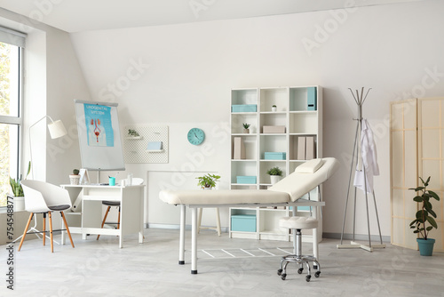 Interior of light medical office with workplace, couch and shelf unit © Pixel-Shot