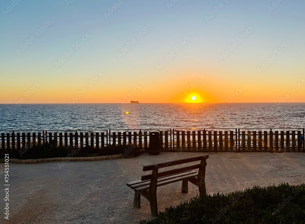 Sunset over the sea with a bench and a cruise ship in the background at Blue Harbour at Malta