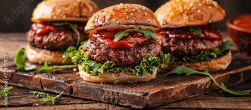 Three juicy beef hamburgers are neatly arranged on a rustic wooden cutting board, accompanied by a generous dollop of ketchup.