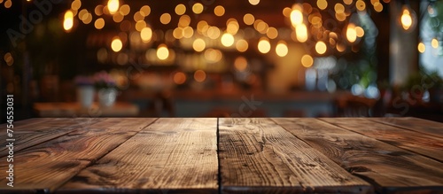 A wooden table top is the main focus of the image, with blurred lights in the background creating a soft glow.