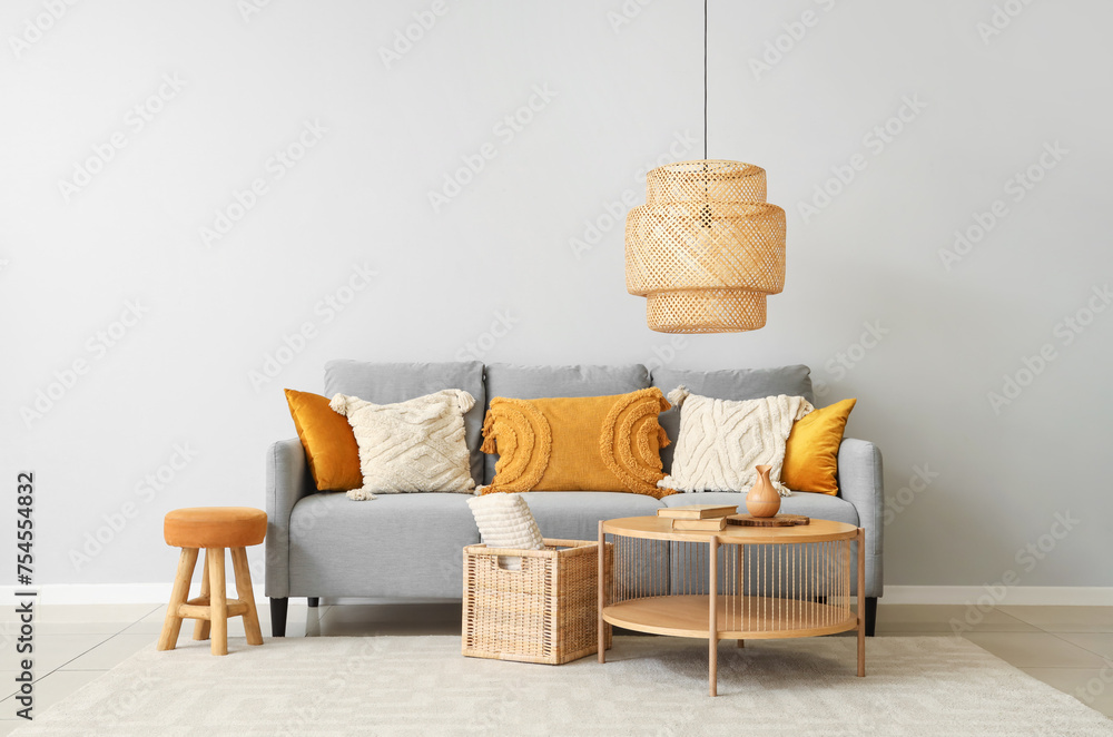 Stylish grey sofa with pillows, coffee table and wicker basket near grey wall - obrazy, fototapety, plakaty 