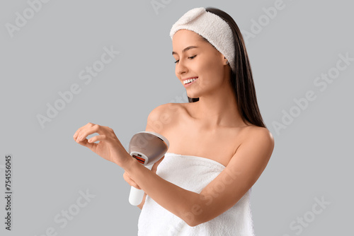 Beautiful young happy woman with photoepilator on grey background