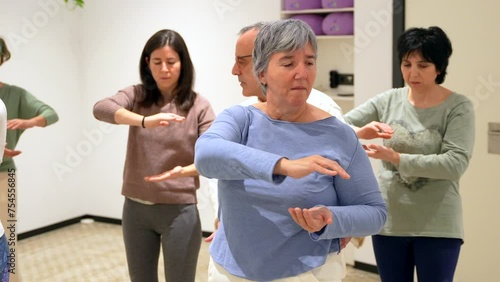 Mature women in a Qi gong class choreographing the exercises moving coordinated photo