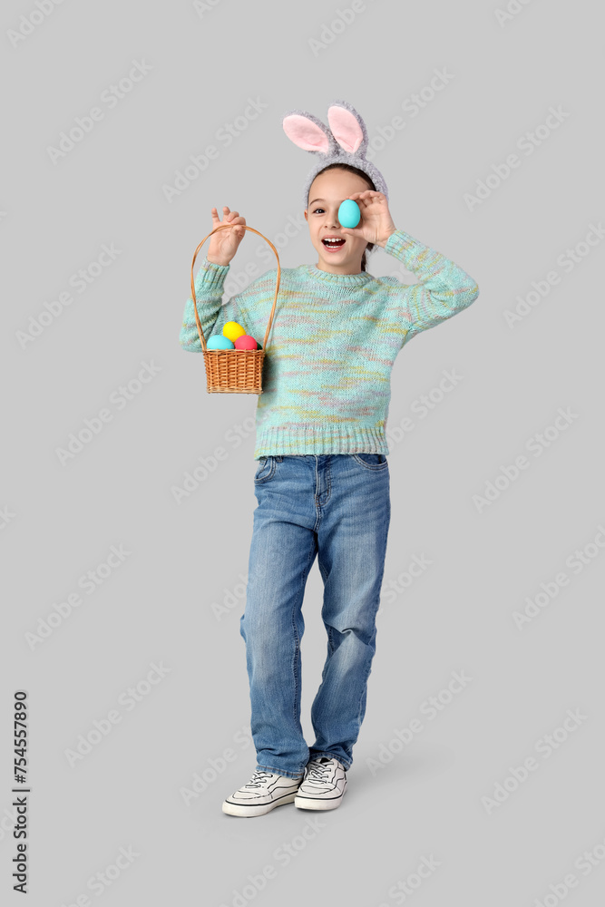 Cute little girl with bunny ears and Easter eggs on grey background Cute little girl with bunny ears and Easter eggs on grey background