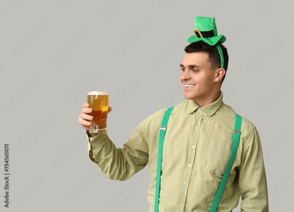 Happy young man with glass of beer on light background. St. Patrick's Day