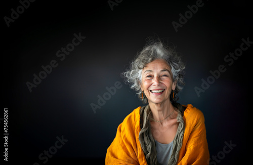 Portrait of Charming Senior Aged Female Retiree With Gray Hair, Wrinkles in Orange Cardigan on Dark Black Gray Background Smiling with Teeth Older Woman. Happy Pensioner, Retirement. AI Generated