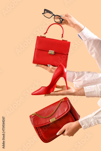 Female hands with stylish women's bags, eyeglasses and high heels on beige background © Pixel-Shot