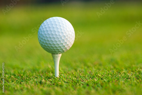 Low angle view of a golf ball on a tee in front of defocused background