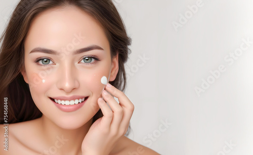 Daily skin care routine. Close-up photo of beautiful Asian model with clean healthy skin applying facial cream beauty product. Skincare and beauty concept, copy space for text. photo