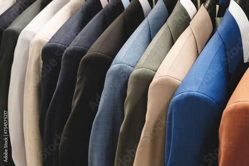 Row of men's suits hanging. Elegant jacket hanged on a clothes rack.