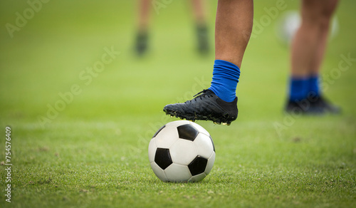 Close up of a foot resting on top of a soccer ball at a soccer field. Good Soccer concept photo