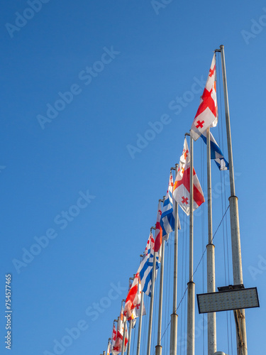 Flags of Georgia and Adjara on flagpoles. Many flags against the sky.