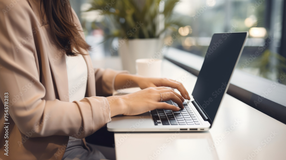 Woman is working on a laptop at a wooden desk in the office Woman is working on a laptop at a wooden desk in the office