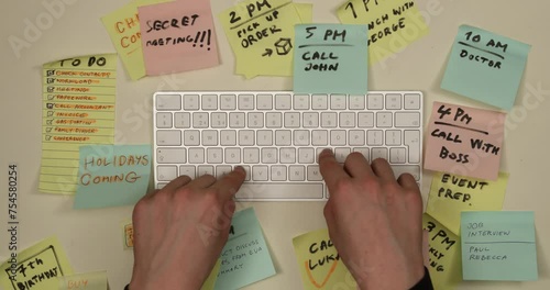 Man typing on keyboard, tasks and to do list appearing on colorful postit papers. Time management and planning concept. Top view, 4K stop motion animation. photo