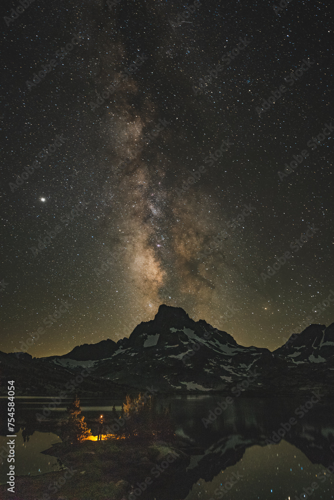 Astrophotography with person holding lighter with the milky way galaxy in the sierra mountains.