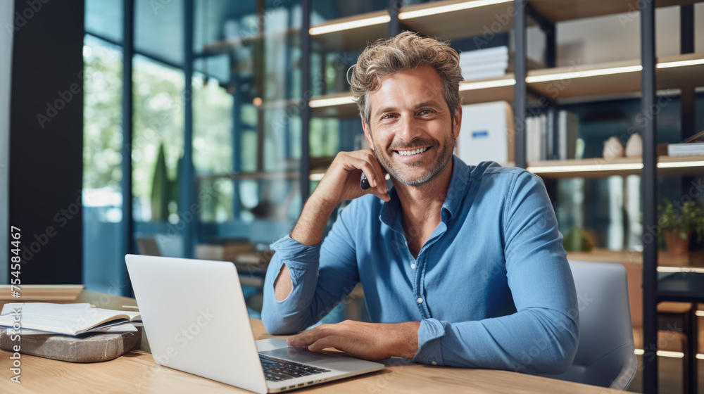 A man in a casual outfit works on a laptop in his office A man in a casual outfit works on a laptop in his office