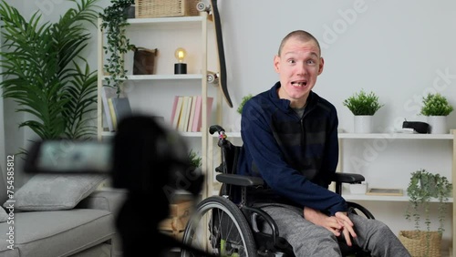 Young man with cerebral palsy talking to camera. Person recording video or live streaming at home.