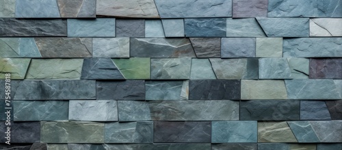 A stone wall constructed with different colored blocks in a trapezoid pattern. The wall showcases a modern style design with green slate stones and cement. photo