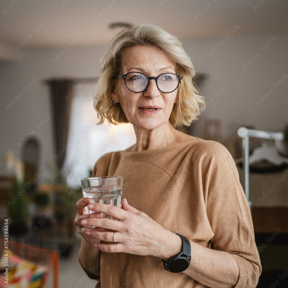 Close up portrait of one mature woman with glass of water at home Close up portrait of one mature woman with glass of water at home