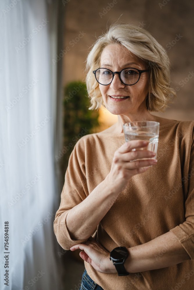 Close up portrait of one mature woman with glass of water at home Close up portrait of one mature woman with glass of water at home
