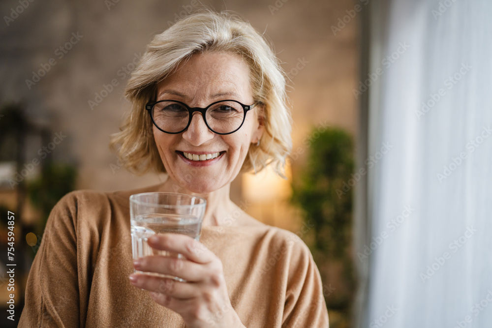 Close up portrait of one mature woman with glass of water at home Close up portrait of one mature woman with glass of water at home
