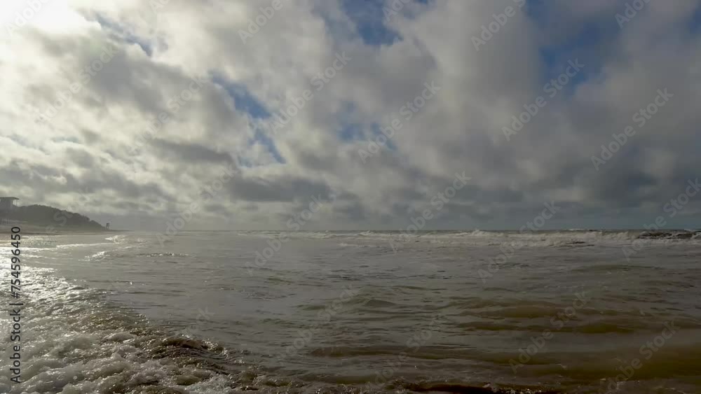 Summer, waves moving gently on the shore of a beach, majestic blue sky with many white clouds Summer, waves moving gently on the shore of a beach, majestic blue sky with many white clouds