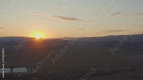 aerial photography. Landscape with a beautiful red sunset against a background of fields and mountains. Cloudy weather and dawn. Country road in green grass