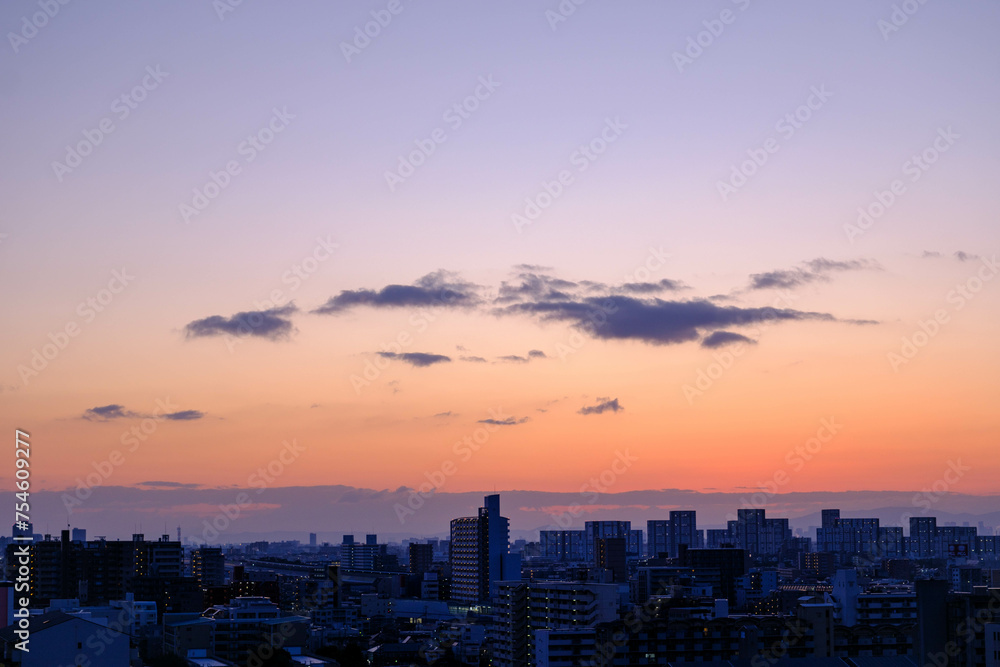 都市の夜明け。神戸市から芦屋大阪方面をのぞむ。生駒の山並みから朝日が昇る。都市のビルがシルエットで浮かぶ。