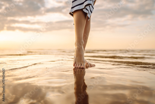 Close- up leg of young woman walking along wave of sea water and sand on the summer beach. Travel, weekend, relax and lifestyle concept. © maxbelchenko