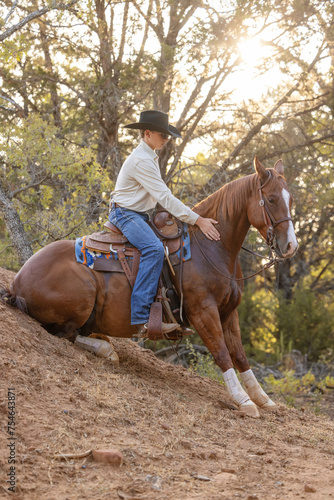 young Cowboy horse trainer riding a sitting horse © Terri Cage 
