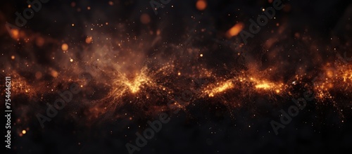 Abstract dark glittering fire embers and sparks creating orange and yellow lights against a blurry black background in motion blur.