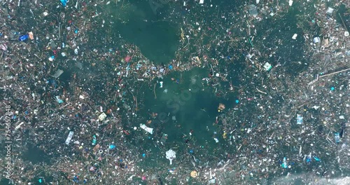 Low altitude top down drone shot of polluted water filled with trash floating over dead coral reef in the turqouise tropical water of Bali Indonesia photo